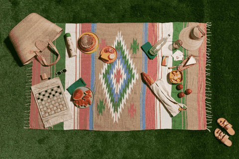 A GIF of a picnic setup-blanket with food, hat, games and a bag