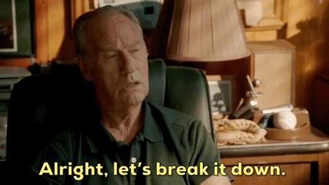  An older man sits in a room and gestures with both hands. He says, “Alright, let’s break it down."