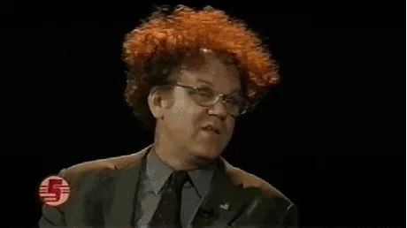A man with red frizzy hair takes off his glasses and has a shocked reaction.