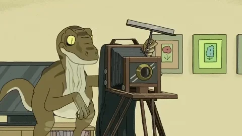 A cartoon of a dinosaur covering under a black fabric to take a picture with an old camera.