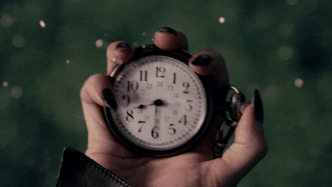 Person holding clock rolls button on the side to make clock hands go back and forth between clockwise and counter-clockwise