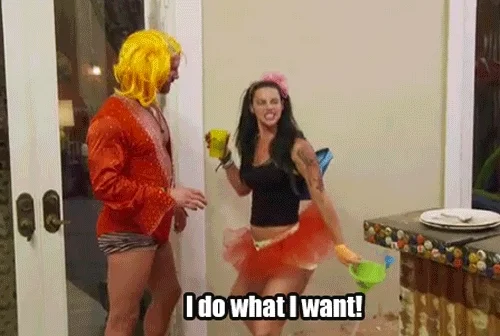 Person wearing tutu holding a drink and beer bong saying 'I do what I want!' standing with other person in a wig.