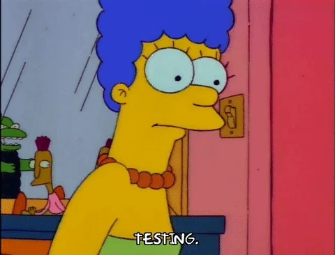 Marge Simpson nervously holds up a microphone and says, "Testing."
