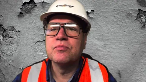 A man in a construction hardhat says, 