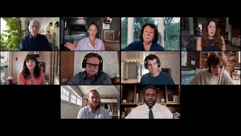 A group of colleagues on a Zoom meeting raise their hands.