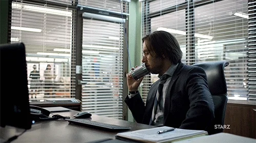 A smiling woman in an office using a tin can phone with a coworker.