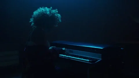 A woman plays an electric piano on a concert stage.