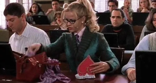 Elle from Legally Blonde pulls out fluffy pen to take notes in heart shaped notebook in a college course. 
