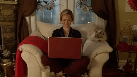 Woman uses on a laptop with a cat sitting beside her.