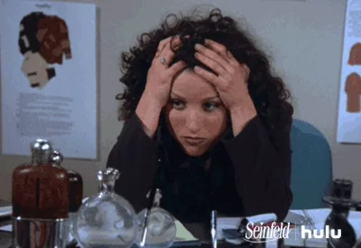 Elaine from Seinfeld is stressed and tired, leaning on desk with hands in hair