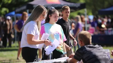 Students in a field on campus signing up for extracurricular activities.