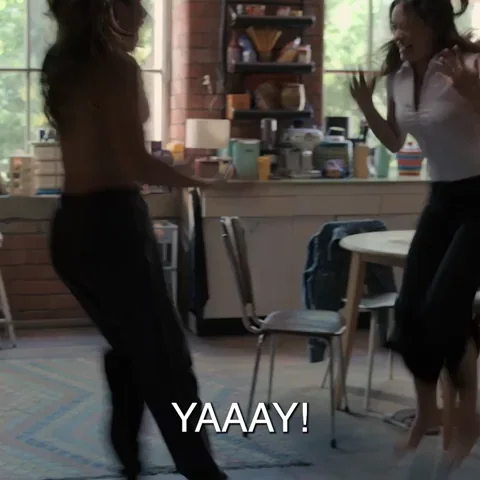 Two girls jumping and hugging in a brightly lit room with the caption, "YAAAY!" at the bottom.