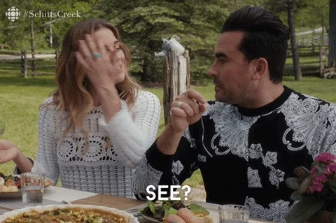 Schitt's Creek Alexis & David, sitting at a table, Alexis saying, 'See? Now this all makes sense!'