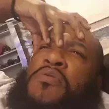 A man holding his hand to his head with a confused look on his face. 