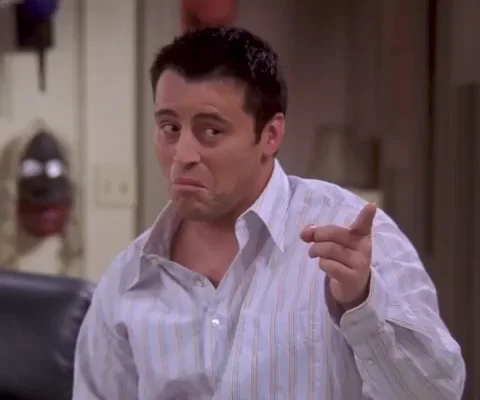 Joey from Friends pointing a finger to his head and smiling to show a smart idea.