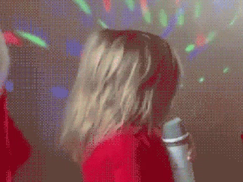 A toddler girl, holding a mic, confidently performing on the stage.