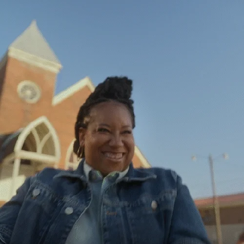 A happy woman dancing outside of a church.