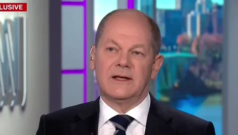 German President Olaf Scholz on the news saying, 'We will act together. He will not be able to split the EU or split NATO.'