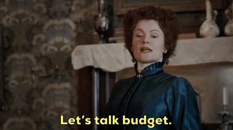 A woman in old clothes saying, “Let’s talk budget.”
