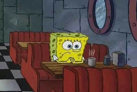 Spongebob sitting at a restaurant table alone, with a frown on his face