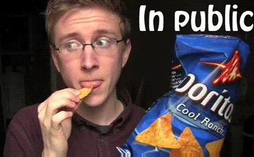 A man at home stuffing Doritos into his face, vs. in public, where he eats it with small nibbles.