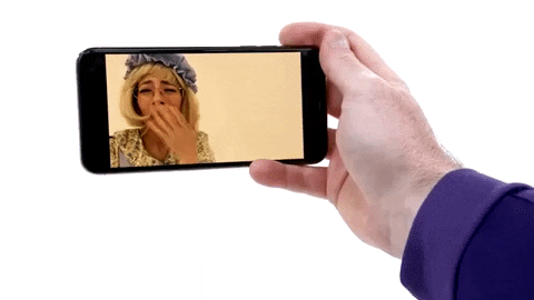 GIF of a hand holding a phone showing video of a woman talking to them