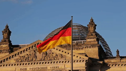 The German Reichstag, with a reunified German flag waving in front of it.
