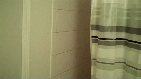 A person angrily looking out from behind  shower curtain