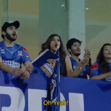 A group of cricket fans watching a match. The camera zooms in on a cheering woman over the text, 'Oh yeah!'