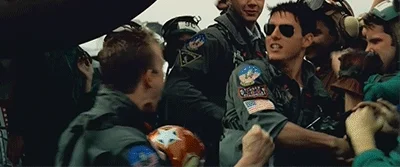 Tom Cruise as Maverick in Top Gun hugs his pilot friends.