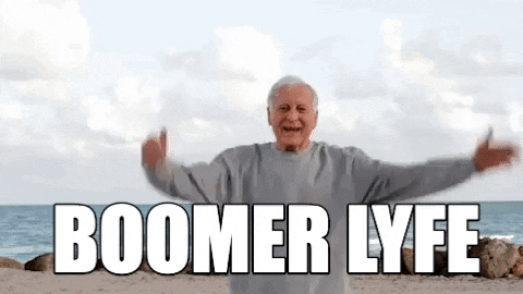An elderly man on a beach throwing his hands up in the air and smiling. The text reads, 'Boomer lyfe'