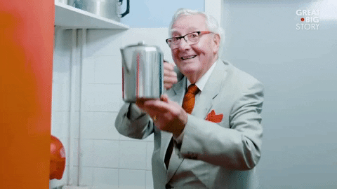 A man in a suit holding up a tea kettle