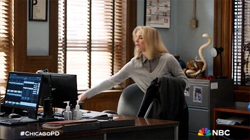 A woman grabbing personal items before rushing out of an office.