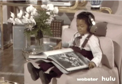 Young child reading book while listening to audio through headphones