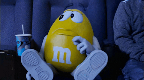 Yellow M&M chocolate candy holding it's stomach while saying 