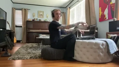 Man shows how to use a floor pillow and ottoman as a chair and desk in a make-shift home office.