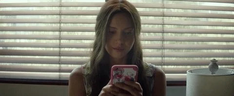 A teen holding her phone and thinking what to respond.