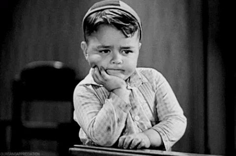 A black and white GIF with a little boy pondering into the distance.
