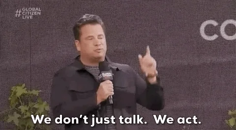 A presenter on a stage at a conference saying, 'We don't just talk. We act.