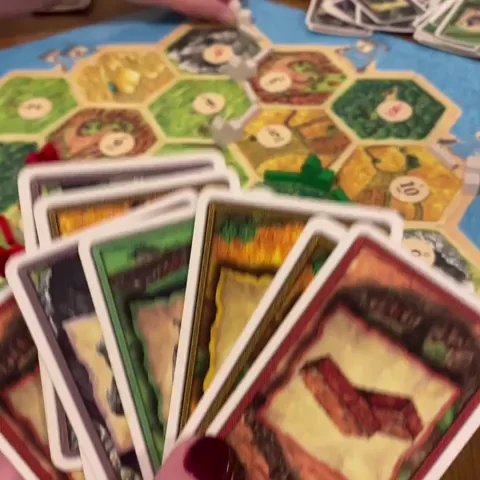 Catan players throwing down their playing cards onto the board.