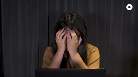 A girl is stressed out and face-palmeing in front of her laptop. The word 
