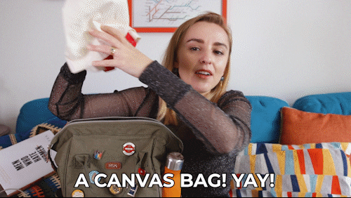 Woman holding a canvas bag while saying 'A canvas bag! Yay!'