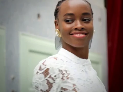 A Black female model turning and smiling in slow motion.