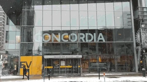 Students walking past a building at Concordia University while it snows.