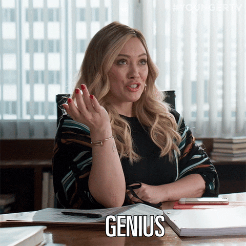Hilary Duff at a desk in an office. She says, 'Genius!'