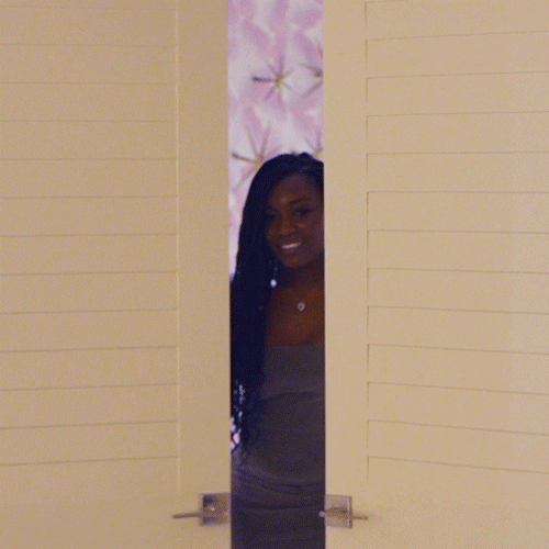 A woman in evening wear opening a double door, making an entrance.