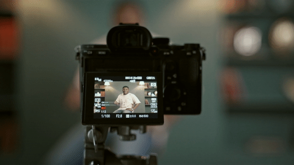 Man behind a a recording camera talking
