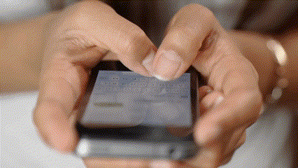 Hands typing a message on a phone.