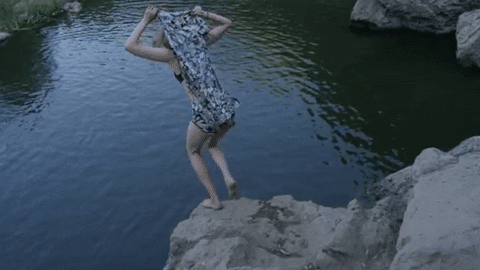 Woman in a bathing suit jumping off a cliff into water