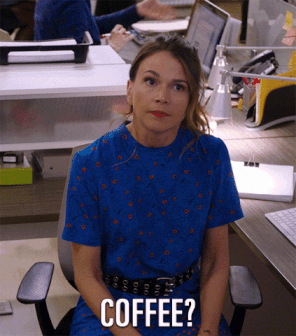 Woman in office standing up. Underneath the words -coffee?